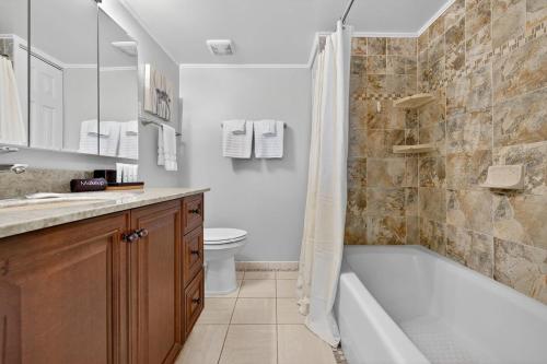 een badkamer met een bad, een toilet en een wastafel bij Ormond Beach Paradise - Steps from no-drive beach in Ormond Beach