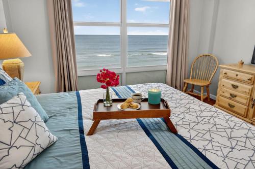 een slaapkamer met een bed en een tafel met een dienblad met eten bij Ormond Beach Paradise - Steps from no-drive beach in Ormond Beach