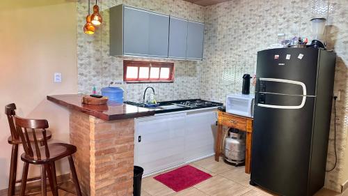 cocina con nevera negra y fogones en Portal da Felicidade, en Maragogi