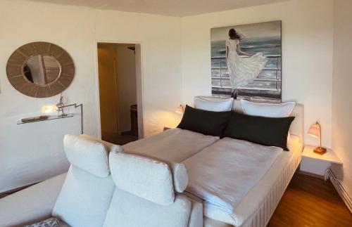 a bedroom with a white bed and a picture of a woman at Lille Koje - Dein eigenes Strand-Apartment mit Panoramablick über die Ostsee in Kronsgaard