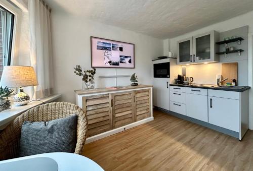 a kitchen with white cabinets and a table with a lamp at Lille Koje - Dein eigenes Strand-Apartment mit Panoramablick über die Ostsee in Kronsgaard