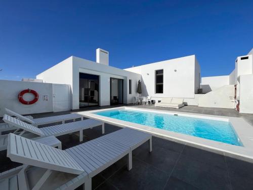 ein Pool mit Bänken und ein Haus in der Unterkunft Casa Blanca - Villa à Teguise avec piscine privée in Teguise