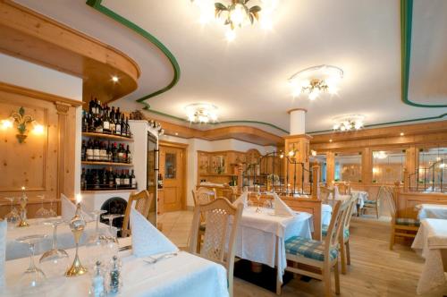 a restaurant with white tables and chairs and wine bottles at Hotel Gianna in Madonna di Campiglio