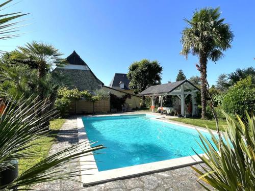 una piscina nel cortile di una casa con palme di Chez castagnet ad Assat