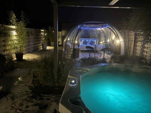Un jacuzzi en un patio trasero por la noche con un iglú en Dôme du puits avec jacuzzi et sauna privatif, en Havinnes