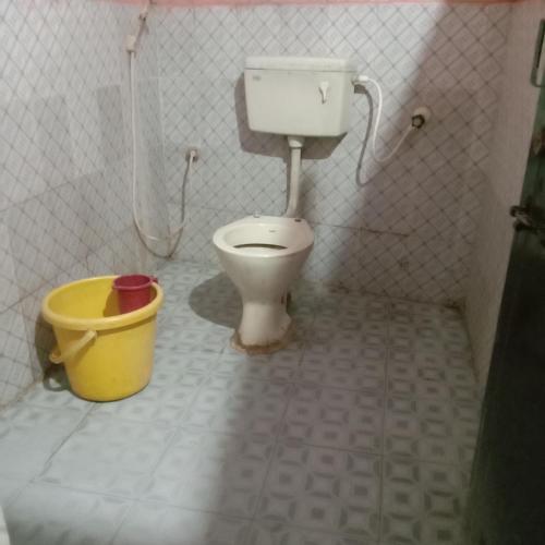 a bathroom with a toilet and a bucket at V R S Dormitory in Hubli