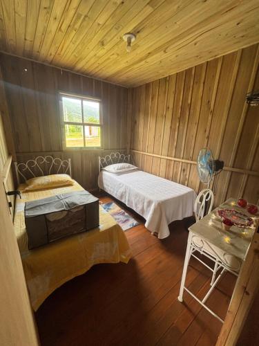 Una habitación con dos camas y una mesa dentro. en Pousada dos Sonhos - Casa Goiabeira, en Timbe do Sul