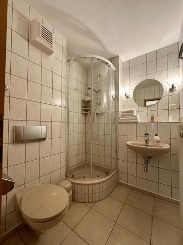 a bathroom with a toilet and a shower and a sink at Hotel La-Pergola in Kolkwitz