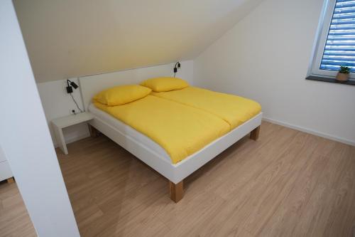 a bed with yellow sheets and pillows in a room at Apartma Ana in Krško