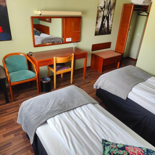 a room with two beds and a desk and a mirror at Highway Hotel in Härnösand