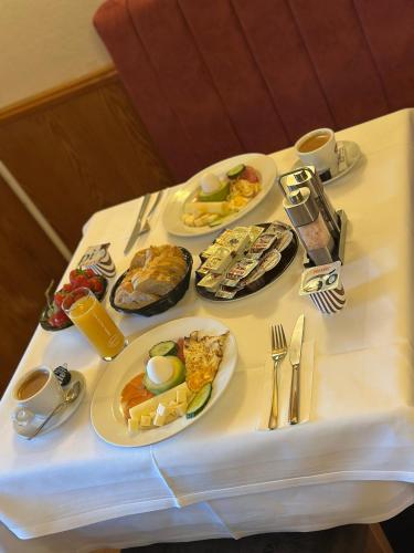 a table with plates of breakfast food on it at Hotel La-Pergola in Kolkwitz