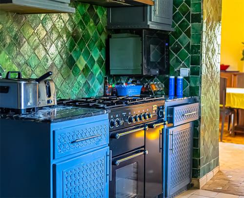 a kitchen with blue appliances and a green tiled wall at Dar Lily, villa familiale avec piscine et services in Skoura