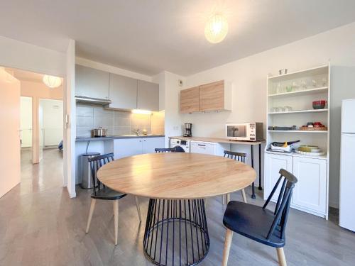 a kitchen and dining room with a wooden table and chairs at Cenon plein ciel in Cenon