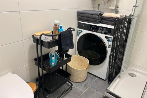 Eine Waschmaschine im Badezimmer neben einem Wäscheständer in der Unterkunft Cozy City Center Designer Apartment for 9 People in Wiener Neustadt