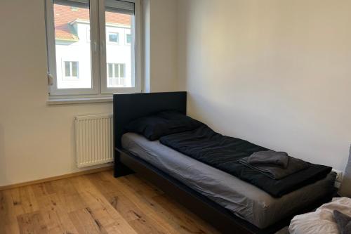 ein Bett in einem Zimmer mit einem Fenster in der Unterkunft Cozy City Center Designer Apartment for 9 People in Wiener Neustadt