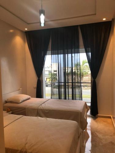 a bedroom with two beds and a large window at Apartment in residence CASABAY in Sidi Rahal