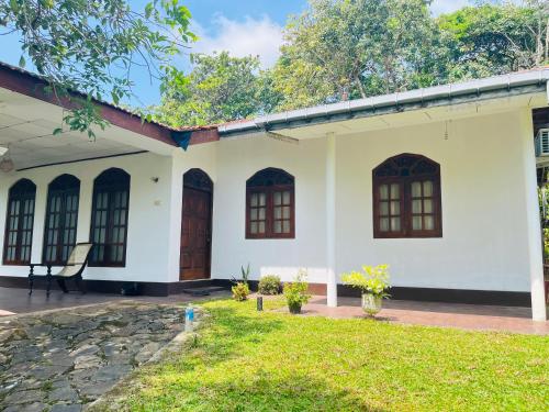 a white house with brown doors and a yard at Coastal breezy bangalow in Weligama