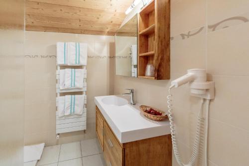 La salle de bains est pourvue d'un lavabo et d'un miroir. dans l'établissement La Perdrix Blanche, à Châtel