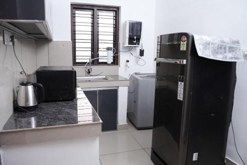 Elle comprend une petite cuisine équipée d'un réfrigérateur noir. dans l'établissement Serene Cottage - Home away from Home, à Vythiri