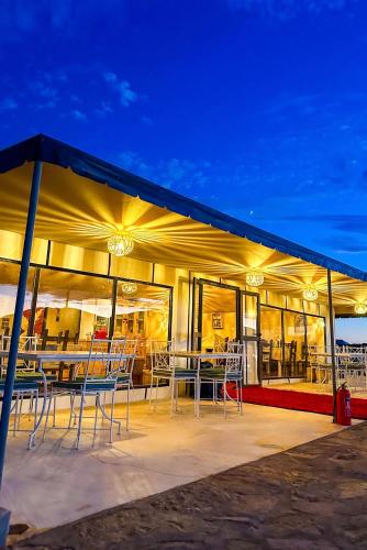 ein Gebäude mit Tischen und Stühlen auf einer Terrasse in der Unterkunft Starlit Luxury Camp in Merzouga