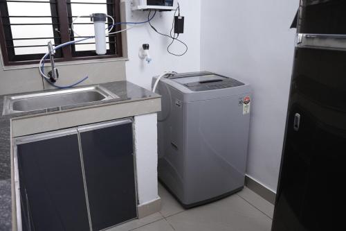 une petite cuisine avec un évier et une machine à laver dans l'établissement Serene Cottage - Home away from Home, à Vythiri