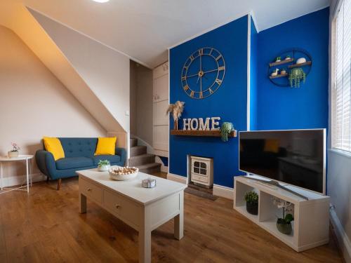 a living room with a blue wall with a clock at Whole Town House - Town centre! in Tamworth