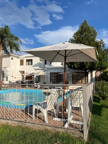 a patio with an umbrella and chairs and a pool at Casa Piedra Hotel in Villa Carlos Paz