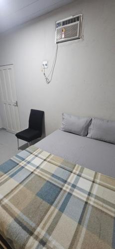 a bedroom with a bed and a black chair at Quarto com otima localização in Manaus