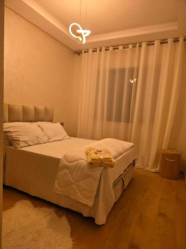 卡萨布兰卡apartment near the beach的一间卧室配有床和白色窗帘的窗户