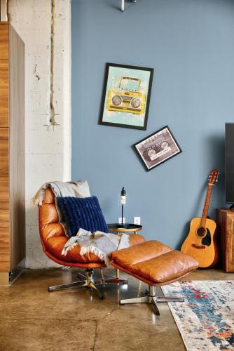 a living room with a leather chair and a guitar at Spacious 1BR loft with flexible group sleeping in Dallas