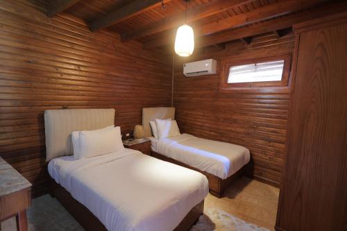2 camas en una habitación con paredes de madera y ventana en La Cabana Beach Hotel Ain Sokhna, en Ain Sokhna