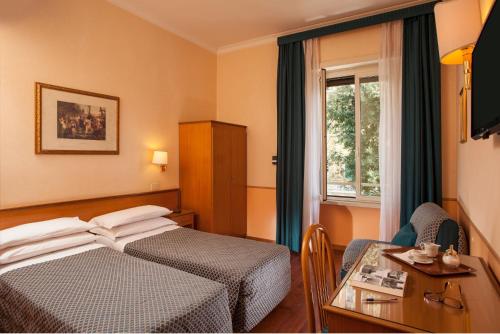 ローマにあるホテル ピエモンテのベッド、デスク、窓が備わるホテルルームです。
