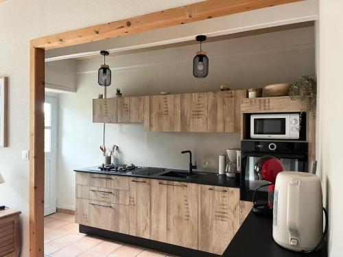 a kitchen with wooden cabinets and a microwave at Le Bas des Landes Gîte in Pléneuf-Val-André