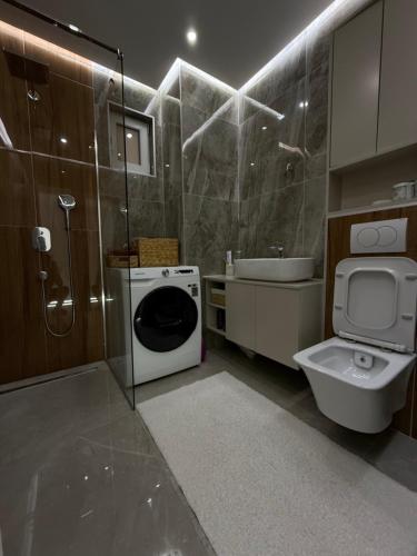 a bathroom with a washing machine and a toilet at Luxury Apartmant Neptun Free Parking in Sarajevo