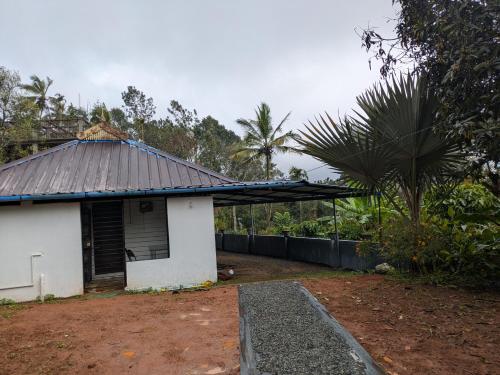 a small white house with a tin roof at Haze Munnar Homestay in Anachal