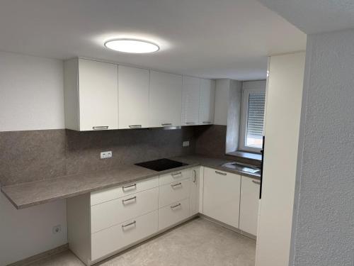 una cucina vuota con armadi bianchi e una finestra di KRAICHGAU # Ein Haus mit 3 Schlafzimmer und Terrasse a Ittlingen