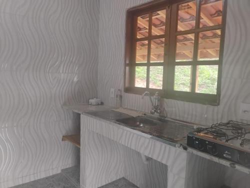 una cucina con un lavandino e una finestra di Chalé alto valinhos a Itamonte
