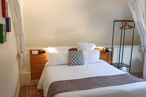 a bedroom with a bed with white sheets and pillows at Les Glycines Vézelay in Vézelay