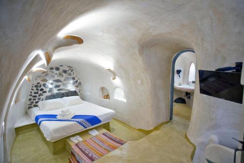 a bedroom with a bed and a tv in a cave at Αura Cave in Fira