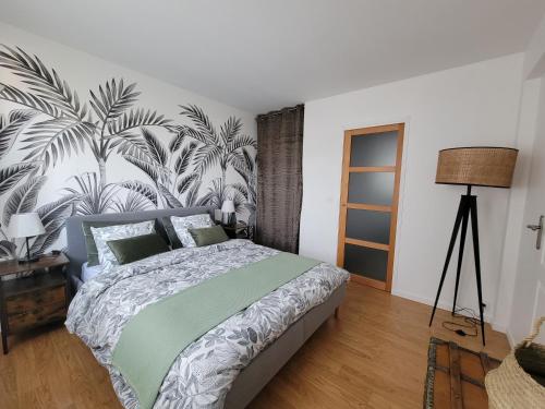 una camera da letto con un grande letto e carta da parati tropicale di Les voiliers a Courseulles-sur-Mer