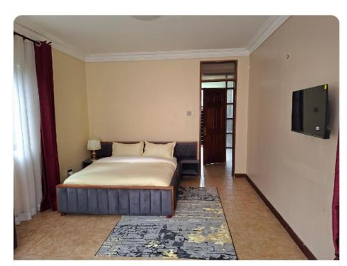 a bedroom with a bed and a flat screen tv at Elma Suites and Lounge in Kampala