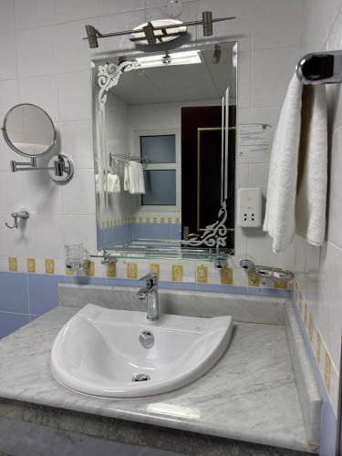 a bathroom with a sink and a mirror at Al Safa Royal Suites in Doha