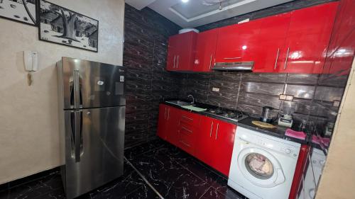 a kitchen with red cabinets and a washing machine at Tayyurt Apartement city centre agadir in Agadir