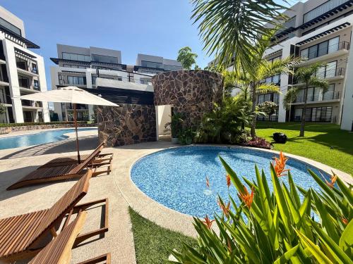 a swimming pool with two benches next to a building at Modern Luxury Residency at Altea-Sunset Pool View in Puerto Vallarta