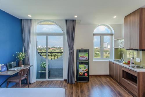 Il comprend une cuisine équipée d'un réfrigérateur, d'une table et de fenêtres. dans l'établissement Fusia Hotel & Apartment, à Đà Nẵng