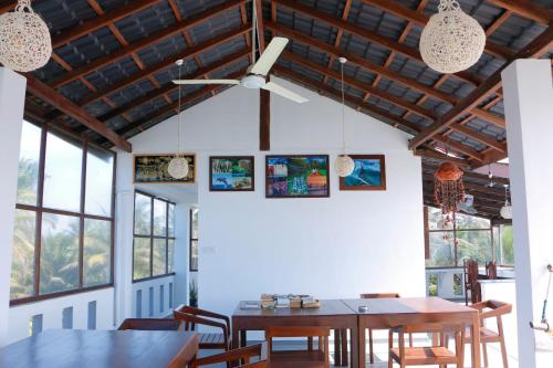 a dining room with tables and chairs and windows at Shehara Sun Surf Lodge in Midigama