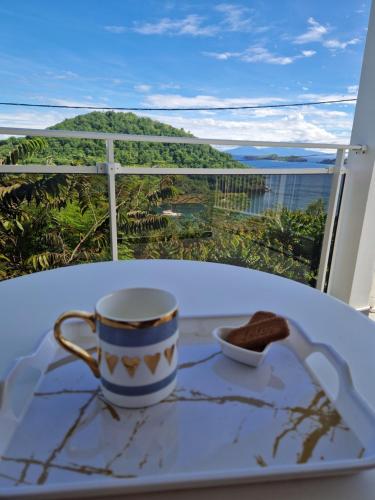a coffee cup on a table with a view of the ocean at Les douceurs de la Baie Terre de Bas in Terre de Bas