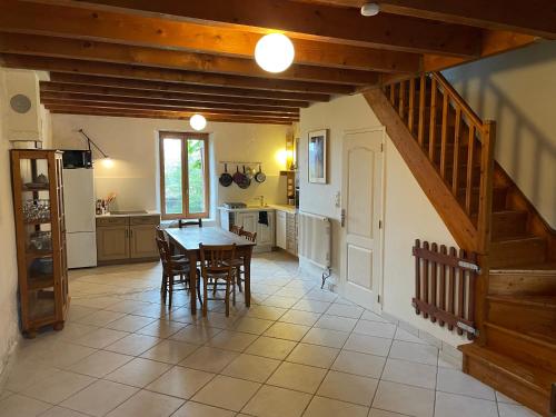 een keuken met een tafel en stoelen en een trap bij 70m2 dans une ferme en Isère in Le Pont-de-Beauvoisin
