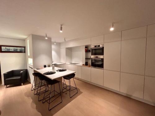 eine Küche mit weißen Schränken und einem Tisch und Stühlen in der Unterkunft Zoute74 - Luxury Penthouse in Knokke-Heist