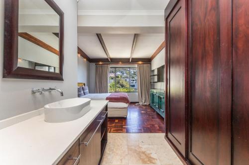 a bathroom with a sink and a bedroom at Sun & Fun In Fresnaye - Family Summer in Cape Town